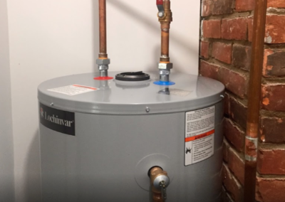 conventional water heater service with brass pipe near brick wall